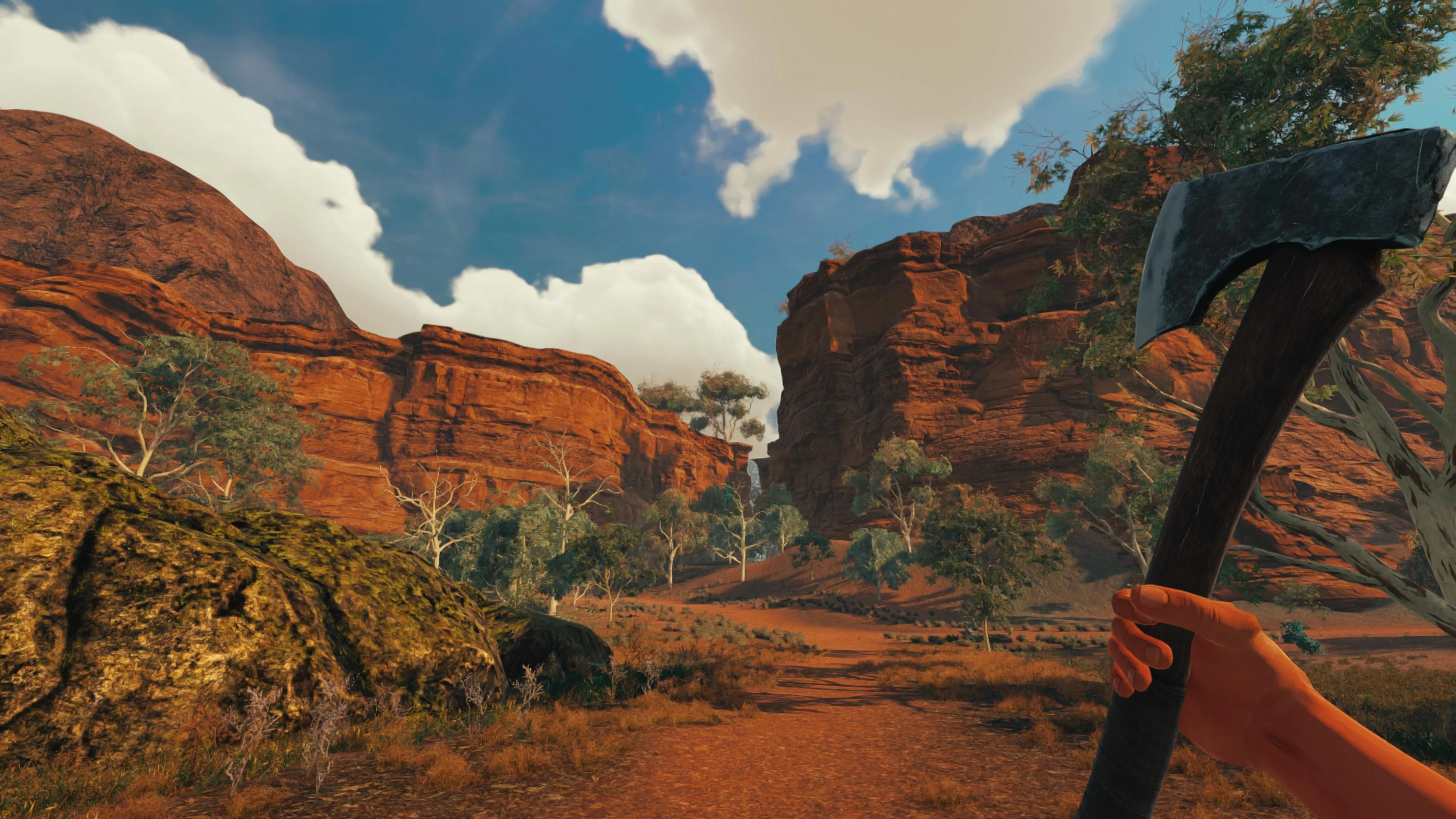 An in-game screenshot of a rugged hand holding an axe against a stunning mountain backdrop.